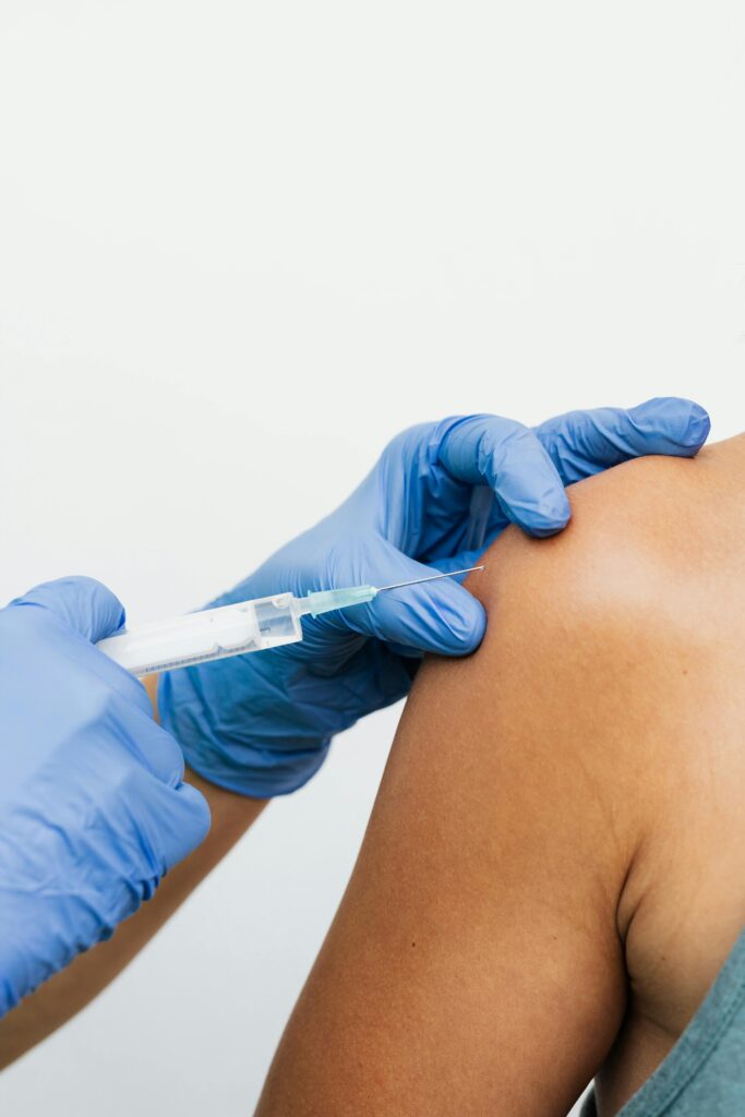 Close-up of a vaccine injection in an arm by a healthcare professional wearing gloves.